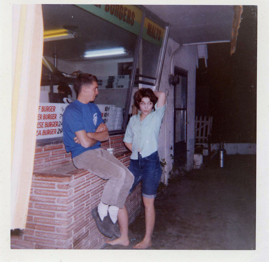 Vintage 1960s color photograph of two young people enjoying food at the original drive-in, capturing the spirit of a classic American summer